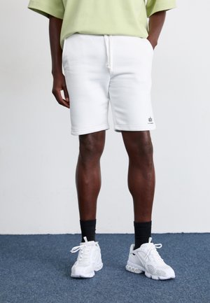 Weiße Baumwollmischung Shorts mit elastischem Bund und Kordelzug. Kombiniert mit weißen Sneakern und schwarzen Knöchelsocken. Schlichtes Design.