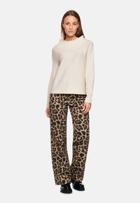 Beige Langarmoberteil mit weitem Kragen, kombiniert mit braunen Leopardenmuster-Hosen, die einen lockeren Sitz und gerades Bein besitzen.