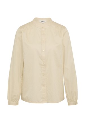 Beżowa bawełniana bluzka z długim rękawem, wysokim kołnierzem i zapięciem na guziki. Miękka tekstura, lekko luźny krój oraz marszczenia na ramionach.