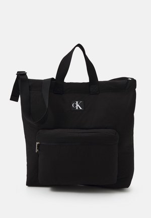 Czarna torba typu tote Calvin Klein z podwójnymi uchwytami, regulowanym paskiem na ramię i przednią kieszenią na zamek.