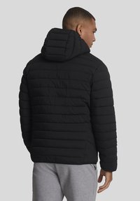 Zwarte donzen jas met horizontaal gestikt ontwerp, voorzien van een capuchon en een gladde, glanzende textuur. Achteraanzicht toont strakke lijnen en geen logo's.