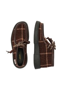 Bruine geruite schoenen met een wolachtige textuur, voorzien van een donkere rubberen zool en bruine leren accenten. Inclusief decoratieve veters.
