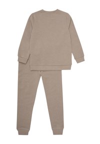 Ensemble de loisirs beige en deux pièces comprenant un haut à manches longues avec des poignets côtelés et un pantalon ajusté assorti avec des poignets élastiques aux chevilles.
