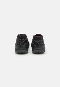 Chaussures de sport noires avec une tige texturée, un soutien du talon moulé et une semelle extérieure en caoutchouc robuste. Comprend des accents réfléchissants pour une meilleure visibilité.