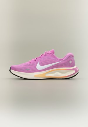 Chaussure de running rose Nike avec un swoosh blanc et une semelle blanche amortie avec des accents jaunes et noirs, présentée sur un fond neutre.
