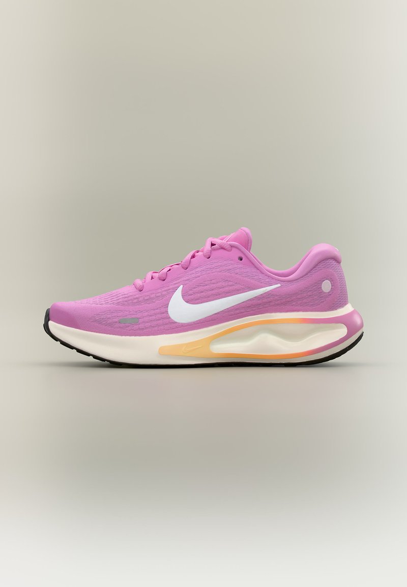 Chaussure de running rose Nike avec un swoosh blanc et une semelle blanche amortie avec des accents jaunes et noirs, présentée sur un fond neutre.