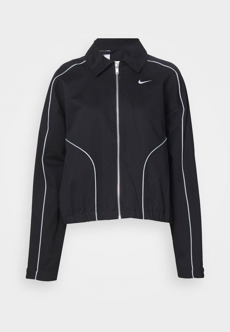 Chaqueta negra de Nike con ribetes blancos en las mangas y el frente, cierre de cremallera plateado, dobladillo elástico y pequeño logotipo de Nike en blanco en el pecho.