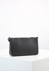 Sort læder clutchtaske med tekstureret overflade, rektangulær form og sølvfarvet lynlås. Har en aftagelig strop for ekstra bekvemmelighed.