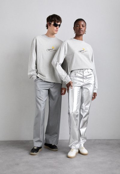Gray long-sleeve t-shirts with logo, paired with shiny silver trousers. Accessories include sunglasses and trainers with contrasting soles.