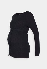 Czarny sweter ciążowy dzianinowy z teksturowanym wzorem w kropki, długimi rękawami, okrągłym dekoltem oraz związanym pasem bocznym do regulacji dopasowania.