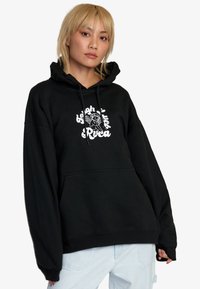 Czarna bluza z kapturem, ze sznurkiem, kieszenią z przodu i białym nadrukiem graficznym. Luźny krój, wykonana z miękkiego materiału, z ribbowanymi mankietami i dołem.