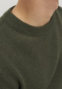 Pull en vert foncé en tissu tricoté texturé. Présente un col côtelé et une coupe décontractée, dévoilant une partie du cou.