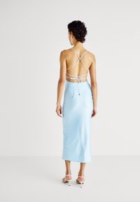 Robe en satin bleu clair avec une silhouette ajustée, des bretelles spaghetti avec un détail croisé au dos, et une longueur mi-mollet.