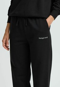 Sorte bomuldssweatpants med snoretræk i taljen, sidelommer og et hvidt logo, i en afslappet pasform og med en glat tekstur.