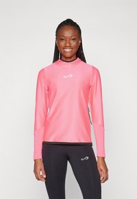 Maglietta sportiva a maniche lunghe di colore rosa brillante, realizzata in materiale testurizzato, con colletto alto e logo sul petto, abbinata a leggings neri.