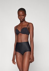 Ensemble de lingerie noire comprenant un soutien-gorge rembourré lisse avec des bretelles ajustables et un bas taille haute. Le matériau semble doux et élastique.