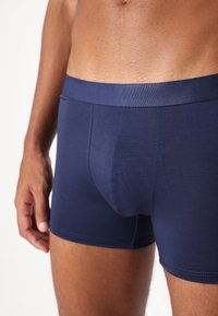 Navy blue cotton boxer briefs with a soft elastic waistband and smooth texture, featuring a front pouch for support and comfort.