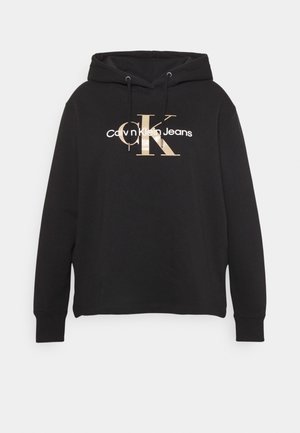 Sort Calvin Klein hoodie med beige "cK" og hvidt "Calvin Klein Jeans" logo på brystet, med lange ærmer og justerbar snøretrækshætte.