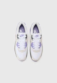 White and light purple Nike sneakers with mesh and suede textures, featuring laces and a prominent logo. Black accents on the sole.