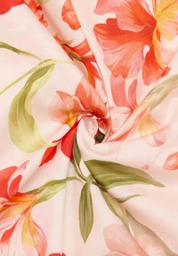 Floral fabric featuring large, vibrant red and orange flowers on a soft pink background, with green leaves interspersed throughout the design.