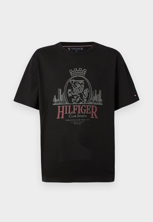 Camiseta negra de manga corta con un diseño gráfico que incluye un león, una corona y el perfil urbano en texto gris y rojo. Textura de tela suave.
