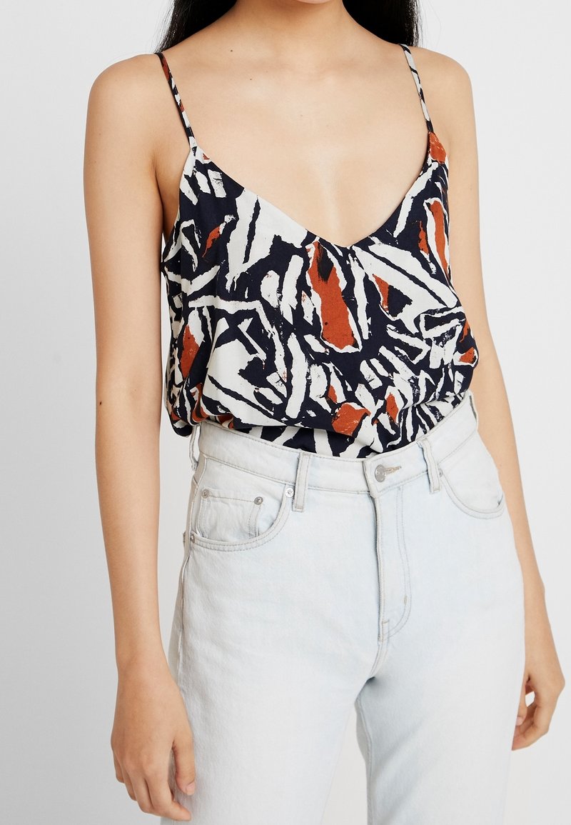 Multifarvet ærmeløs top med en dyb V-hals, prydet med et abstrakt mønster i marineblå, hvid og rustfarvet. Letvægtsmateriale med en afslappet pasform.