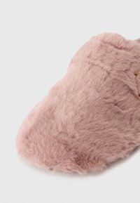 Chausson doux en rose flou avec un bout fermé et une texture en peluche sur un fond blanc uni.