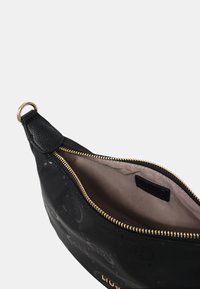 Zwarte leren tas met gouden hardware, voorzien van een ritsluiting en een lichte stoffen voering. Textuur met subtiele logo-details.