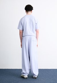Lyse lilla bomulds loungewear sæt med en kortermet top og løstsiddende bukser med elastisk talje og baglomme detaljer.