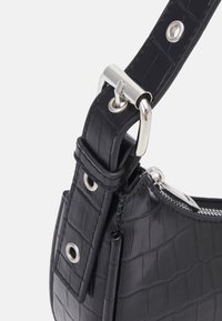 Borsa a tracolla in finta pelle nera con motivo coccodrillo. Presenta hardware in argento, tracolla regolabile e apertura con zip. Dettaglio della superficie testurizzata.