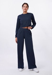 Ensemble de détente bleu marine en tissu doux, comprenant un haut court à manches longues et un pantalon large avec une taille élastique.