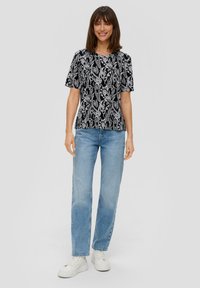 Zwart-wit gestreepte top met korte mouwen en ronde hals, gecombineerd met lichtblauwe jeans met rechte pijpen en witte sneakers. Eenvoudig ontwerp.