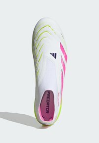 Chaussure de sport blanche avec des accents néon verts et roses, dessus texturé et design à enfiler. Présente un logo noir proéminent sur le côté.