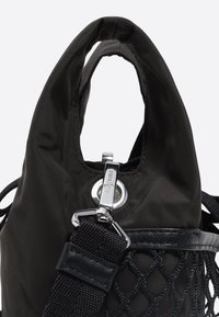 Bolsa de nylon negra con una parte superior curva, herrajes plateados, acentos de malla y una correa texturizada. Presenta un cierre de clip y costuras reforzadas.