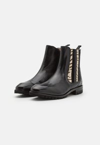 Botas chelsea de cuero negro con paneles laterales elásticos texturizados con un patrón a rayas, punta redondeada y suela de goma para mayor agarre.
