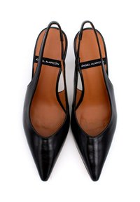 Tacchi slingback in pelle nera con punte affusolate, caratterizzati da lati intagliati e solette color panna. Etichetta del marchio visibile sulla cinghia nera.