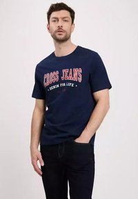 Granatowa bawełniana koszulka z okrągłym dekoltem, z czerwonym i białym napisem „CROSS JEANS” oraz „DENIM FOR LIFE” w pogrubionej czcionce.