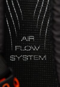 Étiquette en tissu noire affichant le texte « AIR FLOW SYSTEM » en blanc, avec des lignes subtiles au-dessus pour le design. Le texte est écrit dans une police moderne et facile à lire.