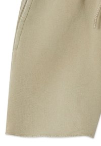 Close-up van beige gebreide korte broek met tailleband met trekkoord en zijzaknaad.