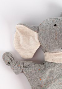 Gray fabric elephant plush toy with cream accents, knotted arms, and speckles of orange and green. Soft texture, rounded shape, large ears.