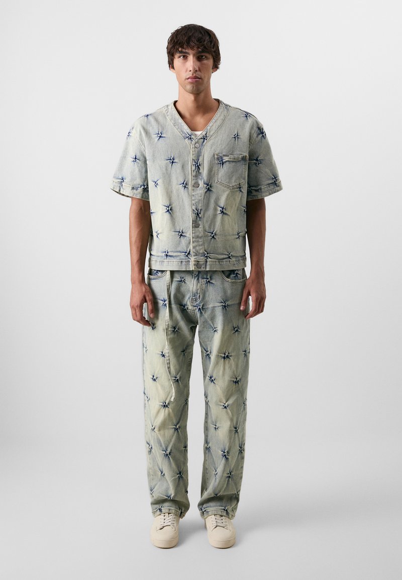 Helehelesinine denim särg ja püksid, millel on tähtede moodi muster, rinnatasku ja nööbid. Looduslikult vaba lõikega, pehme tekstuuriga.