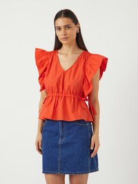 Rød, kortærmet top med rynkede skuldre og en samlet talje, parret med en blå denimskørt. Ren, glat stoftekstur.