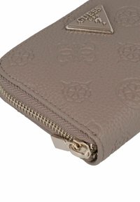 Grijze leren portemonnee met een gestructureerd oppervlak, voorzien van geperste bloemmotieven, een ritssluiting en een driehoekig metalen merkembleem.