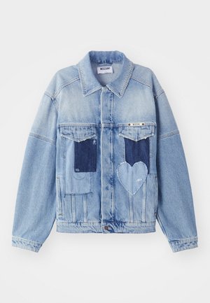 Ljusblå denimjacka med mörkblå lappar, inklusive en hjärtformad lapp på framsidan, samt knappstängning, liggande platt.
