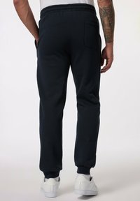 Pantalones de chándal azul marino hechos de una tela suave, con una cinturilla elástica, puños en los tobillos y un bolsillo trasero en el lado derecho.