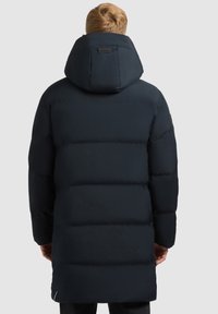 Lang marineblå pufferjakke med hætte, med en quilted design, glat tekstur og et synligt logo på nakken.