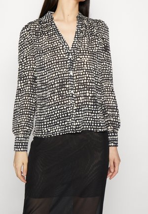 Schwarz-weiße Bluse mit Polka-Dots, V-Ausschnitt, langen Ärmeln, Knopfverschluss und gerafften Details an den Schultern. Leichter, halbtransparenter Stoff.