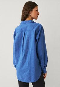 Blauwe button-up shirt met een relaxed fit, lange mouwen, een plooitje aan de achterkant en een afgeronde zoom, gemaakt van lichte stof.