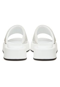 Paire de sandales blanches à plateforme avec une large bride et des semelles noires, vues de dos sur fond blanc.