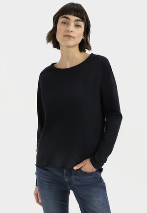 Zwarte katoenen top met lange mouwen, ronde halslijn en relaxte pasvorm, gecombineerd met blauwe jeans. Gladde textuur en eenvoudig ontwerp.